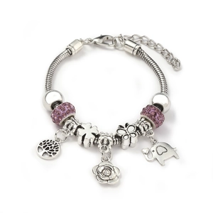 Detail of silver snake chain bracelet with purple charms featuring tree of life and butterfly
