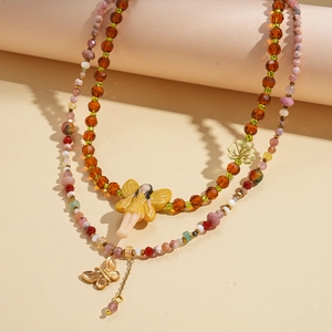 Macro shot of double-layered beaded necklace with fairy, butterfly and leaf pendants