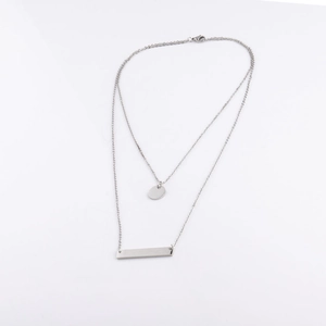 Detail of silver double-layered necklace with round disc and bar pendant on white background