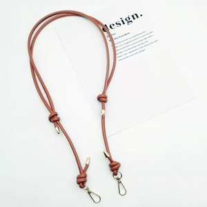 Detail of adjustable brown leather bag strap with gold metal buckles and knotted design