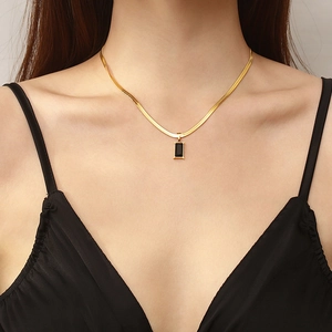Dettaglio della collana a catena serpente dorata con pendente nero rettangolare su modella