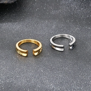 Detailed top view of gold and silver V-groove stainless steel rings on a grey texture
