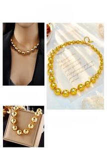 Detail view of gold bead necklace with gradient sizes, polished finish and extension chain