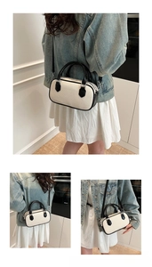 Detail shot of mini Boston bag with cream canvas and black leather accents on a model