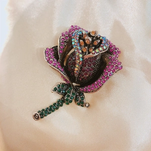 Vintage rose flower brooch with pink rhinestones on champagne velvet background