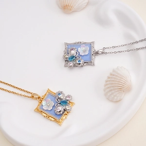 Monet style butterfly pendant necklace in gold and silver with blue gems and floral details