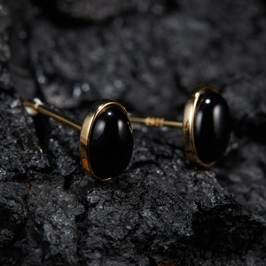 Detailed macro view of gold-plated 925 silver stud earrings with oval black jasper stones
