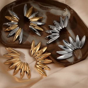 Radial jagged leaf earrings in polished gold and silver finish on silk fabric