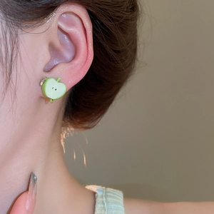Close-up of green enamel apple slice stud earring worn by model with metallic stem details