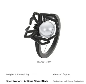 Macro detail of gothic matte black spider ring featuring a centered white round pearl