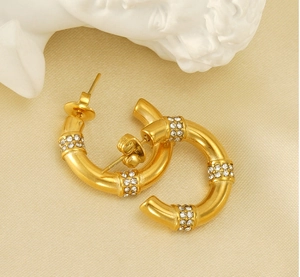 Detail of C-shaped gold-plated hoop earrings featuring three sparkling diamond-set sections