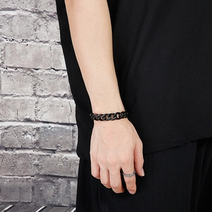 Close-up of a black stainless steel Cuban link bracelet on a male model wrist