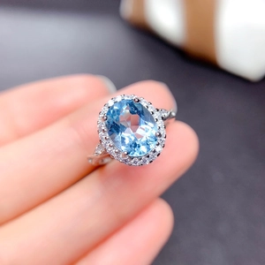 Macro shot of a classic silver halo ring featuring a large oval blue topaz stone