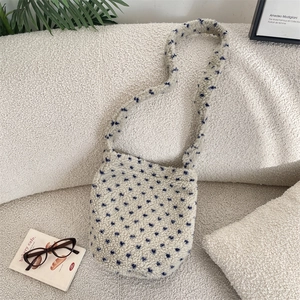 Detailed view of plush lamb wool bucket bag with blue floral pattern on white couch.
