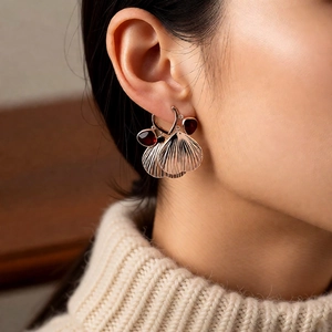 Close-up of vintage gold fan tassel earrings with red teardrop stones on a model