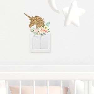 Detail of a golden unicorn and pink floral wall sticker above a white light switch