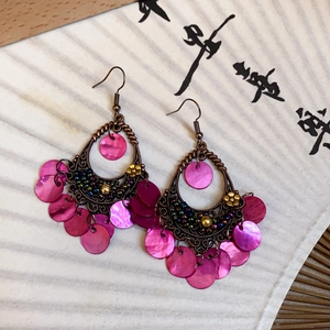 Detail of ethnic drop earrings with bronze filigree, blue beads and purple shell tassels