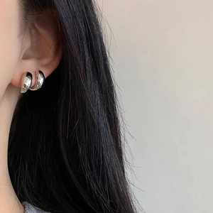 Close-up of sleek silver waterdrop earrings on model's ear showing polished finish