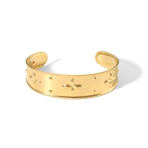 Close-up of golden bangle with embossed clover patterns and detailed knurled edges