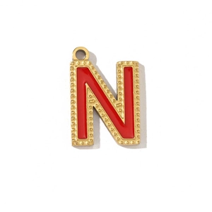 Detailed close-up of a red enamel letter N pendant with gold beaded trim and hanging loop