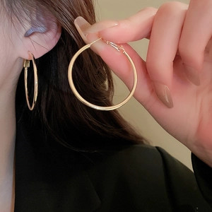 Close-up of elegant large golden hoop earrings worn by a model in warm soft lighting