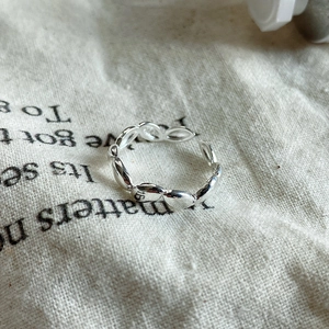 Macro shot of minimalist sterling silver droplet chain ring on beige linen background