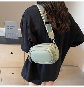 Light green crossbody bag with dual zipper layers and stylish wide fabric strap