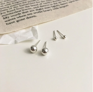 Close-up of different sized 925 sterling silver ball stud earrings on white fabric