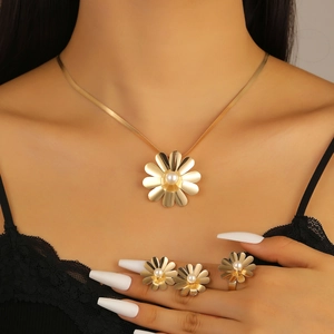 Detailed view of golden flower jewelry set with pearls on a model wearing black lace