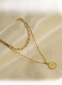Macro detail of 18K gold stainless steel paperclip chain and round letter H pendant