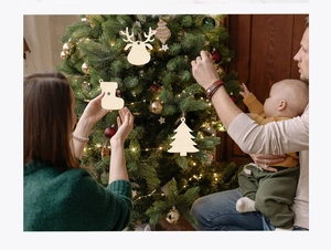 Famille décorant un sapin avec des ornements en bois de renne et de chaussette