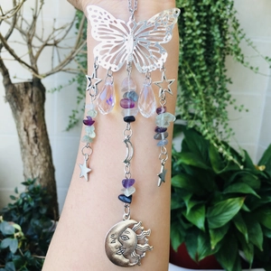 Detail of silver butterfly suncatcher with colorful crystal beads and moon charm on arm