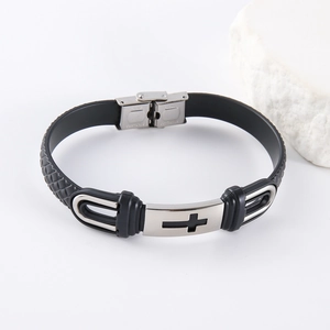 Détail d'un bracelet en silicone noir avec breloque croix en acier sur support en pierre