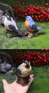 Statuine di uccelli in resina con piume realistiche su basi di pigne e ghiande decorative