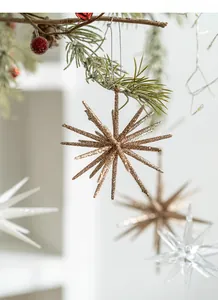 Close-up of champagne gold starburst ornaments hanging on frosted pine tree branches