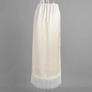 Detailed close-up of cream satin skirt with elegant lace hem and elastic waistband
