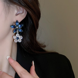 Detail of blue and white double flower earrings featuring zircon crystals on a model