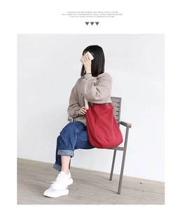Lifestyle shot of large red canvas tote bag held by a model in a minimalist setting
