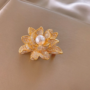 Close-up of 14k gold plated flower brooch with sparkling zircon petals and central pearl