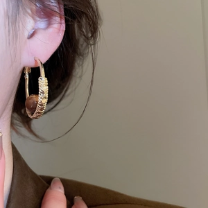Detail of vintage gold hammered hoops with brown tiger eye stone beads on a model