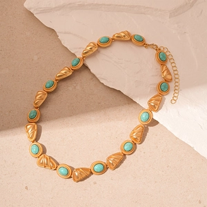 Detail of vintage gold necklace with turquoise stones and shell charms on stone base