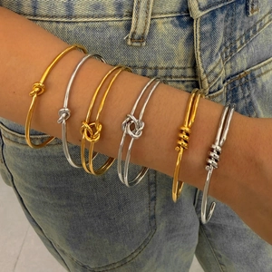 Bracelet jonc minimaliste à nœud en acier inoxydable or et argent porté au poignet