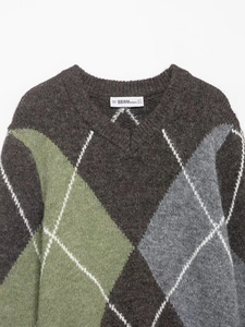 Detailed macro view of the knitted argyle pattern and round neckline on a brown sweater