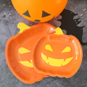 Detailed view of Halloween pumpkin face paper plates set on dark marble tabletop