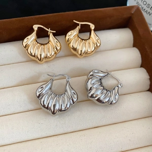 Macro view of gold and silver croissant dome hoop earrings with ribbed texture in a jewelry box