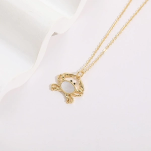 Macro detail of golden crab pendant featuring white shell inlay and zircon accents