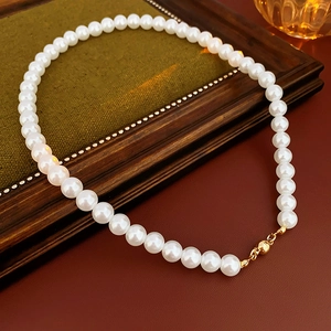 Detail of vintage pearl necklace with magnetic gold clasp on classic wooden background