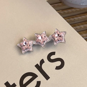 Close-up of stars hair clip with pink heart-shaped crystals and white enamel on silver base
