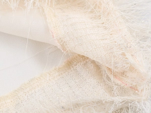 Detailed macro view of beige fringe fabric with shimmering silver lurex threads
