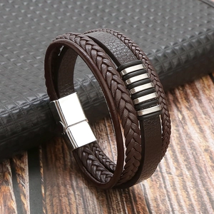 Detail of multi-layer brown braided leather bracelet with silver magnetic clasp on desk